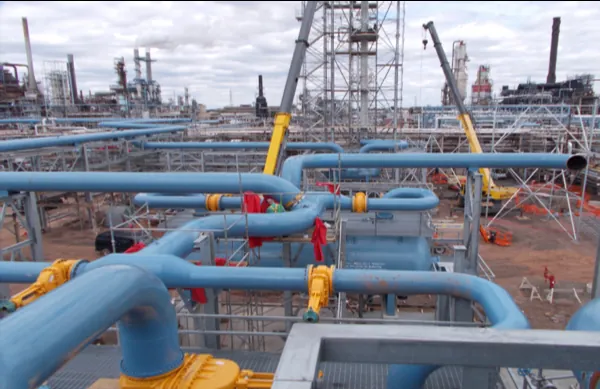 Crawler crane setting a new flare stack beside a refinery pipe rack